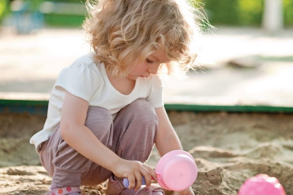 ребенок играет в песочнице 