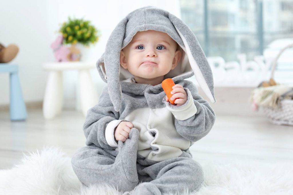 ребенок в костюме зайчика ест морковку